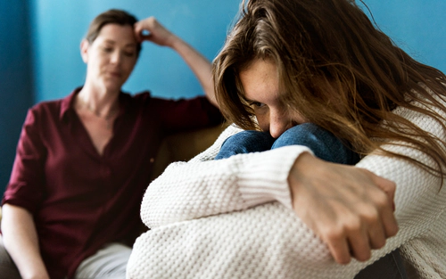 Daughter in foreground distraught, mother in background hopeless