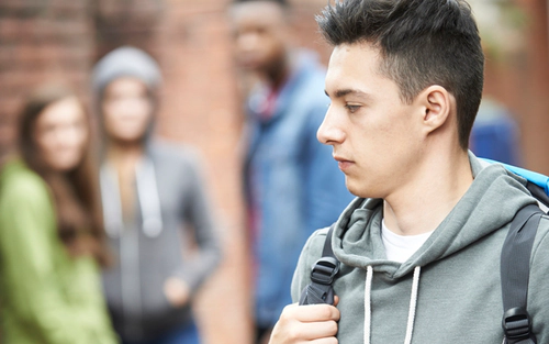 Young adult with looking as if something to hide with onlookers in background